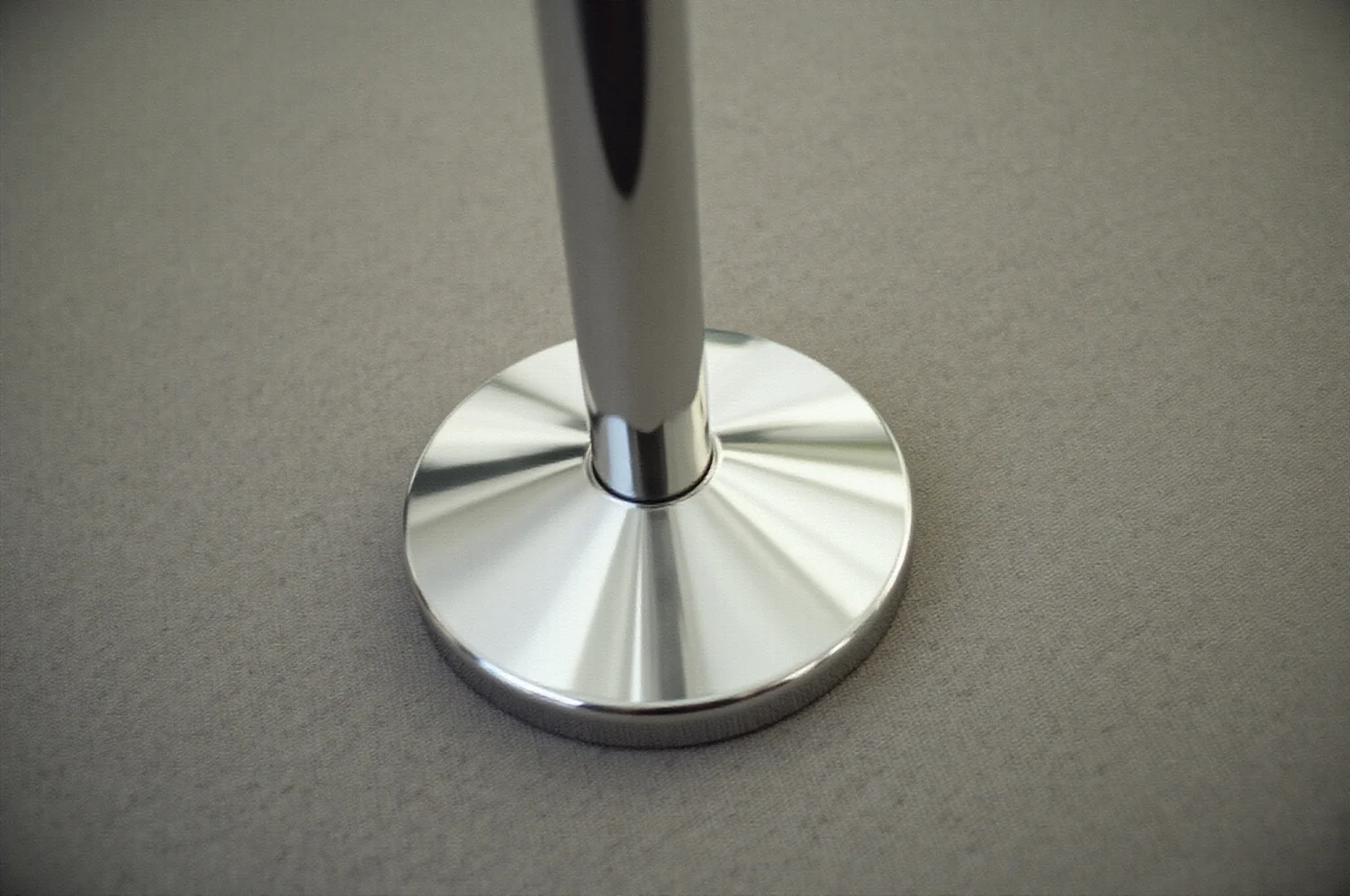 The chrome base of a stanchion on the carpet of an empty stand, seen from above